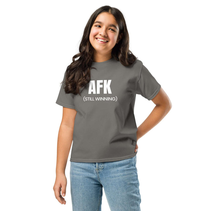 AFK Youth classic tee on a smiling girl in a grey t-shirt, featuring bold white print saying AFK (STILL WINNING).