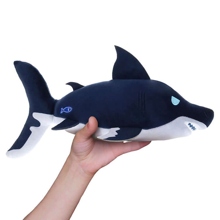 Hand holding a plush Megalodon toy from the Fisch Deluxe Collectable Plush series.